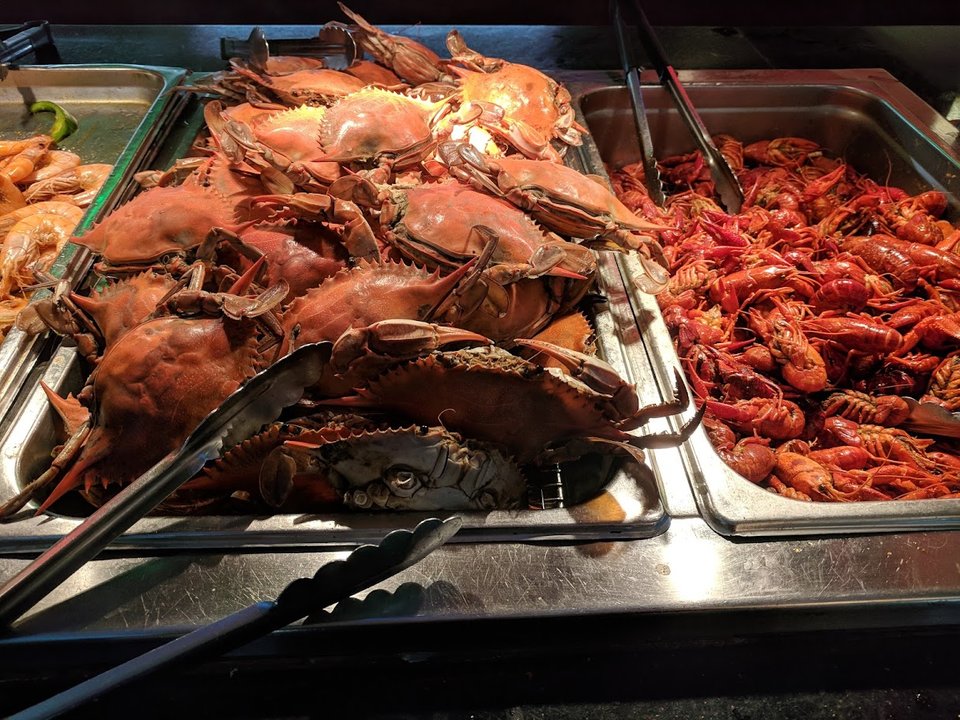 Buffet trays with hot dishes under bright lights.